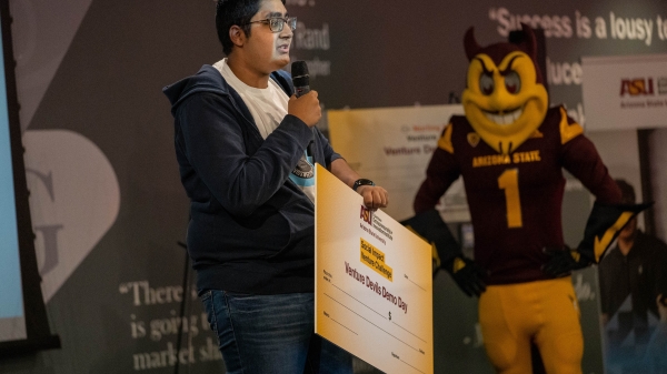 Young man holding microphone and oversized check.