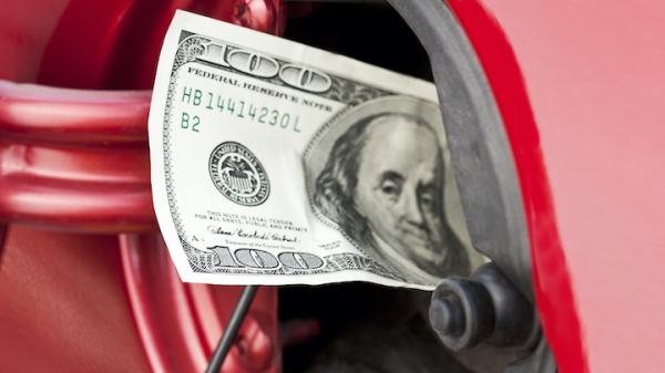 U.S. $100 dollar bill sticking out of a car's gas cap.