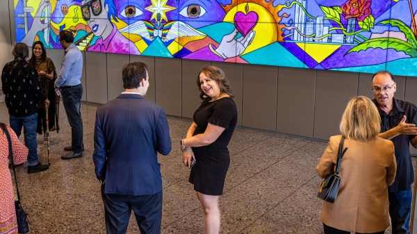 People socializing in lobby with bright, colorful mural displayed on wall behind them
