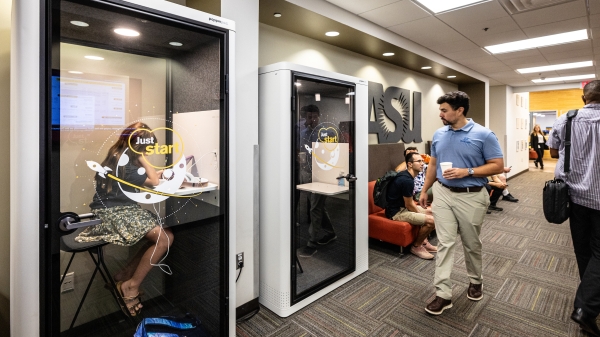 People working in private booths and open seating in an incubator space.