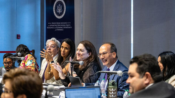 People seated at a table speaking into microphones.