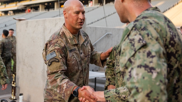 Two men in military fatigues talking and shaking hands.