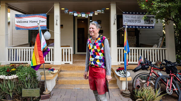 Man standing in front of house with banners welcoming him home after US bike ride