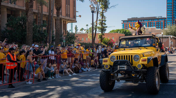 Sparky waving from Jeep to crowd during Homecoming Parade