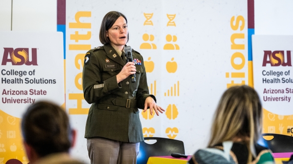 A woman in an Army uniform speaks before an audience