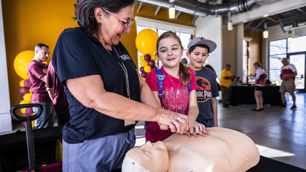 Woman teaching two children CPR on test dummy