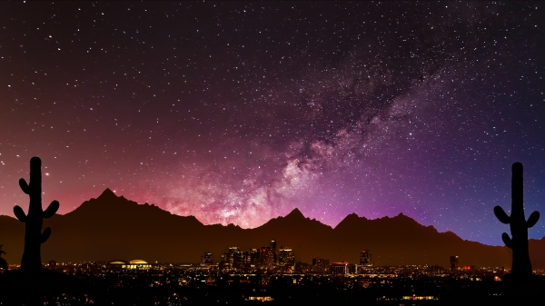 Colorful night sky showing Milky Way with silhouette of Arizona mountains and saguaros in foreground