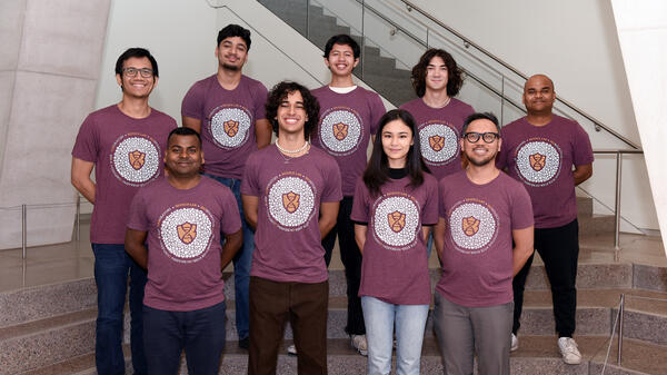 Group of people wearing the same shirt pose for a photo in front of a staircase.