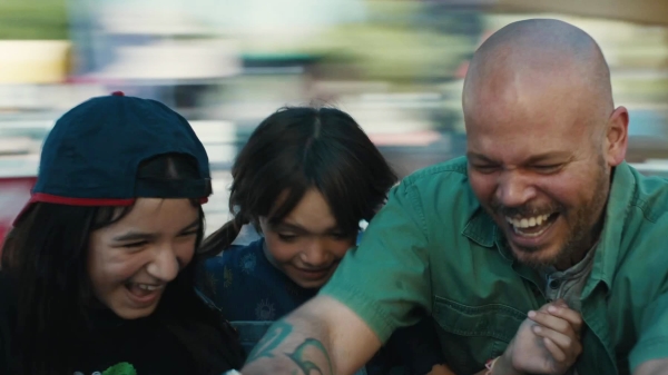 Still from the movie In the Summers showing a dad laughing with two young daughters