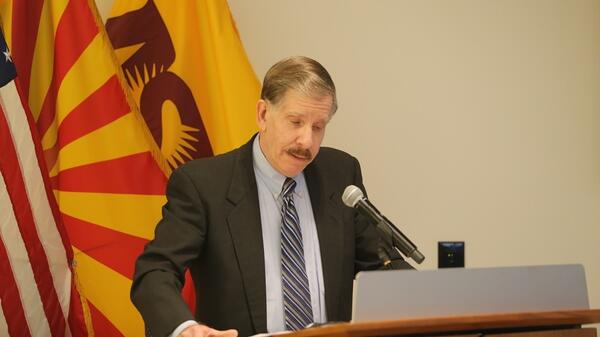 Eli Rosenbaum speaking at a lectern