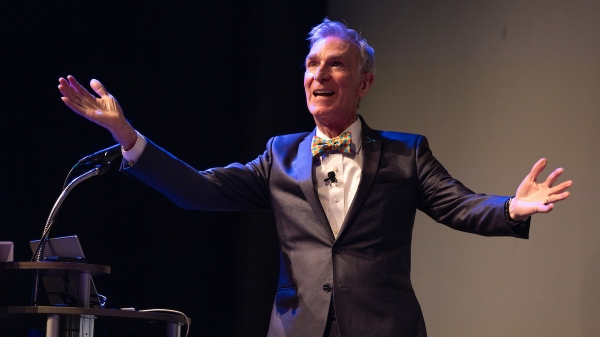Bill Nye holding his arms outstretched toward an unseen audience.