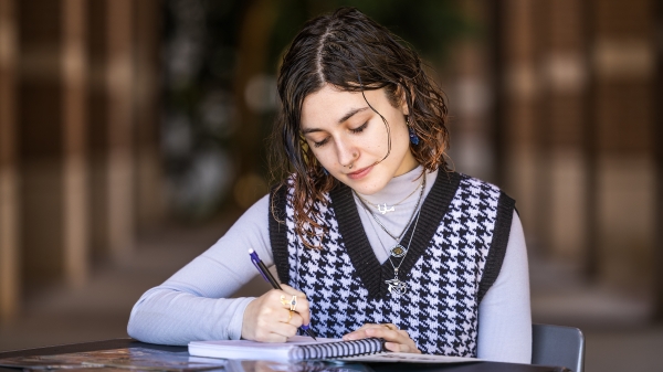 Young woman sketching in a notepad at a table