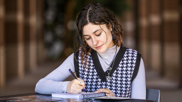 Young woman sketching in a notepad at a table