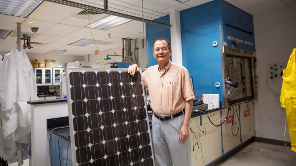 Meng Tao standing next to a solar panel.