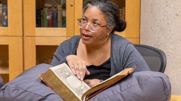 ASU professor Brandi Adams looking at book with John Milton's handwriting
