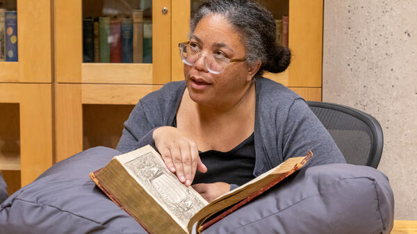 ASU professor Brandi Adams looking at book with John Milton's handwriting