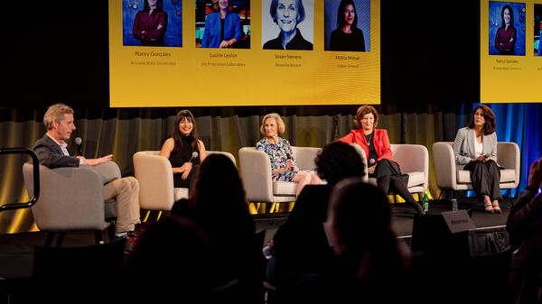 People seated on a stage during a panel discussion.