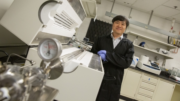 Researcher posing next to machinery in a lab.