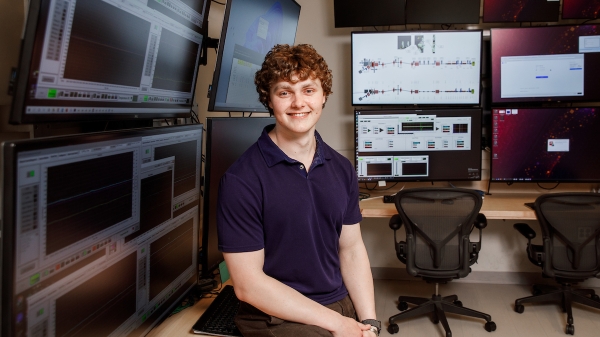 Adam Kurth sits on a desk in the Biodesign lab