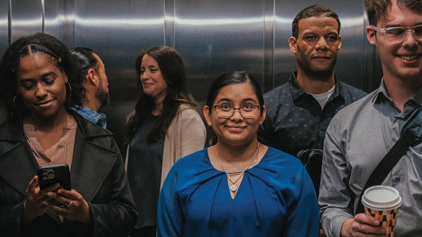 Woman in blue top in elevator with group of people