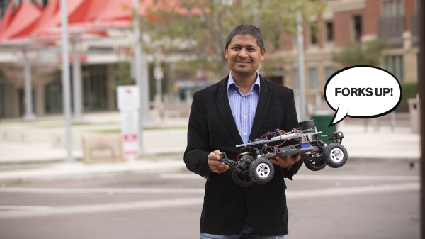 Aviral Shrivastava holding a model car with an illustrated speech balloon that says "Forks Up!"