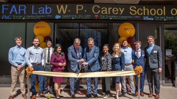Students and leaders cut a large ribbon with a banner overheard reading "FAR Lab W. P. Carey School"