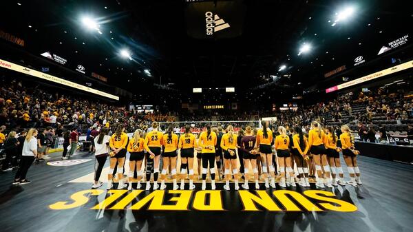 The ASU women's volleyball team is seen from behind as they stand on the court for the national anthem