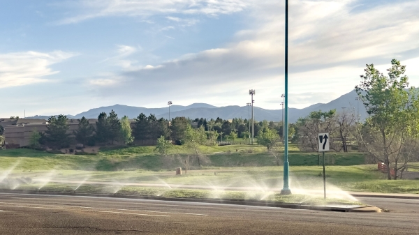 A Gilbert, Arizona, park with grass and trees being watered with sprinklers.
