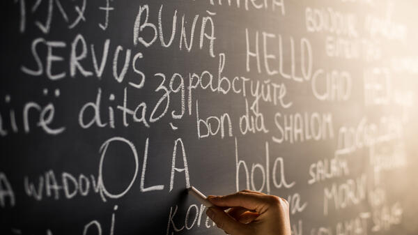 The word "hello" written in different languages on a chalkboard.