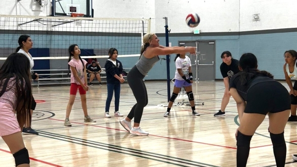A group of girls in a gym playing volleyball