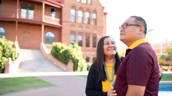A mother and father gaze at each other on a college campus.