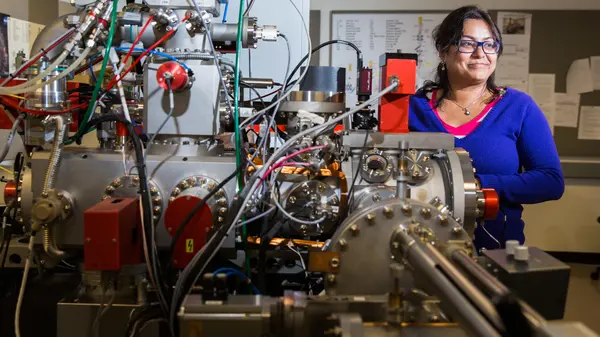 Maitrayee Bose poses with NanoSIMS 50L at Arizona State University.