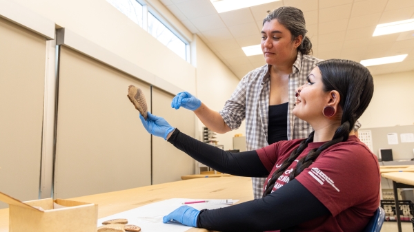 Two people observe an artifact