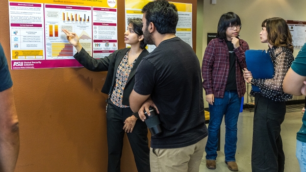 Student presenting a research poster to curious onlookers.