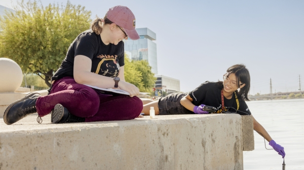 Two students taking water samples from a lake.