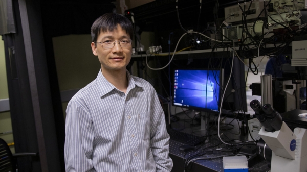 ASU Associate Professor Chao Wang in a lab next to a computer and a microscope.