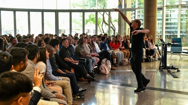 People seated in an auditorium listening to a man speaking.