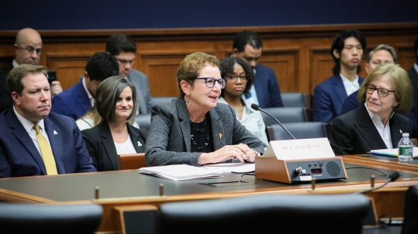 Older white woman with short brown hair and black glasses in a gray suit sits behind a committee desk in a congressional hearing