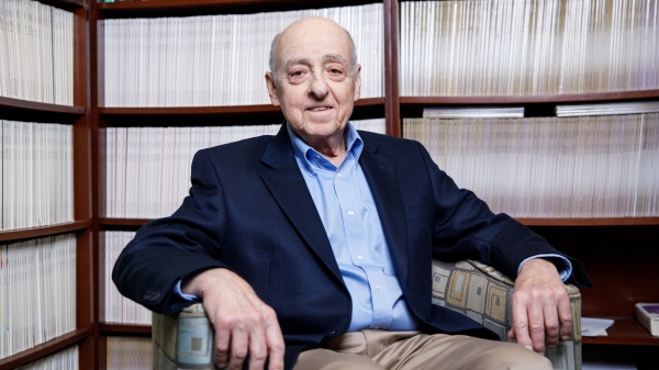 ASU Professor Sidney Hecht  sits in a chair in front of bookcases