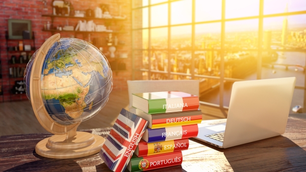 A globe sits on a desk next to foreign language books.