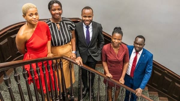 Group of five Black men and women posing for photo on staircase