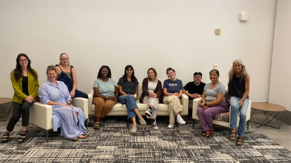 Group of people posing for a photo while seated on couches.