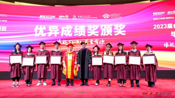 Group of people standing on a stage wearing graduation regalia.