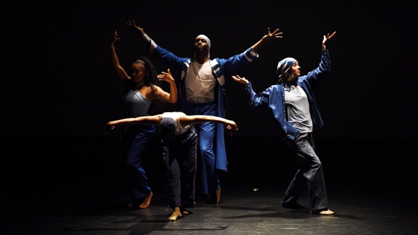 Dancers stand in various poses on stage