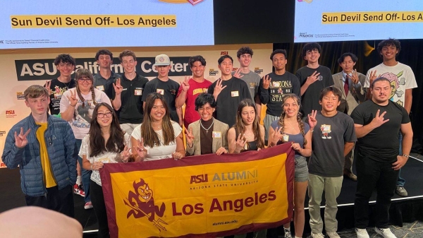 Group of young adults pose for a photo holding an ASU-branded banner.