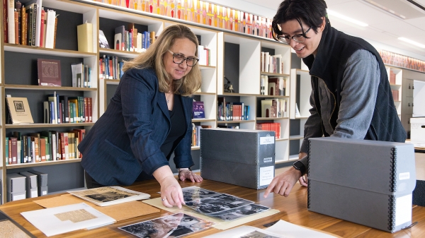 Two people in a library looking through old photos.