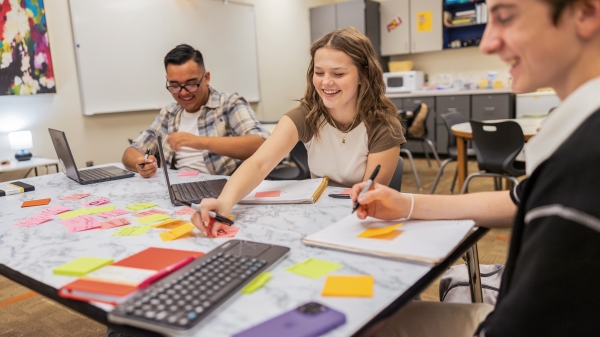 High school students working together with colored post-its at a table in a classroom