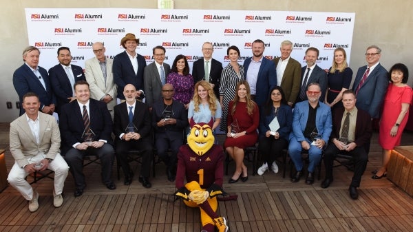 A group of people with awards smile for a picture with Sparky at the helm