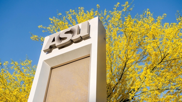 An ASU sign stands in front of flower-laden palo verde branches.