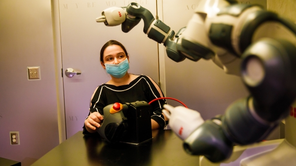 An ASU researcher experiments with a robot at a university laboratory focused on human, artificial intelligence and robot teaming.